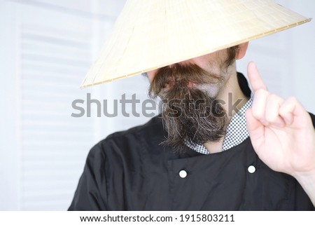 A hilarious parody of an Asian man in Vietnamese hat with a beard. Portrait. Asian cafe chef.