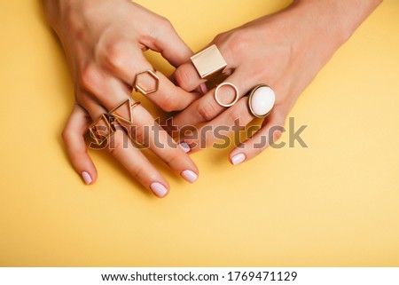 woman hands with manicure and jewelry ring on yellow background, beauty style concept