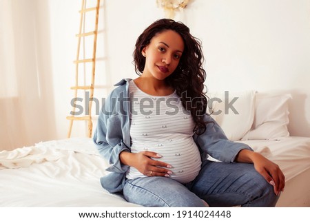 young pretty african american woman pregnant laying in bed, lifestyle people concept