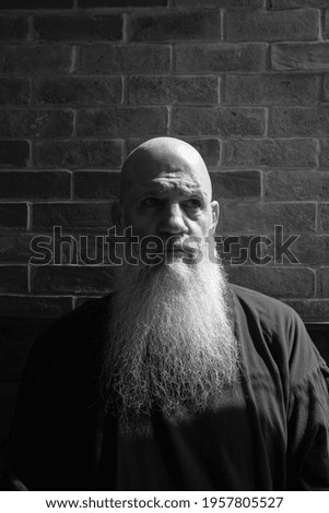 Black and white portrait of mature man with long gray beard thinking