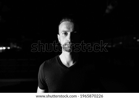 Portrait of handsome man at night in parking lot building shot in black and white