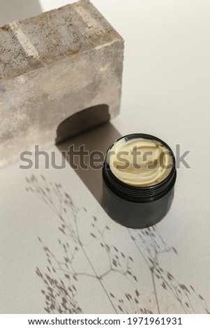 Cosmetic cream container with face or body cream on neutral background