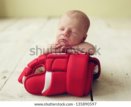 Cute newborn baby boy sleeping on a hockey glove