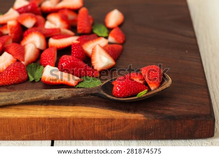Strawberries being prepared on a unique handmade cutting board.