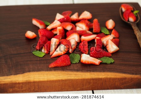 Strawberries being prepared on a unique handmade cutting board.