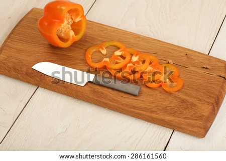 Orange sweet pepper being prepared on a unique cutting board.