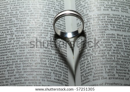 Wedding ring casting a heart onto a bible. \