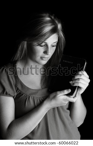 Teen with bible on black background, low key lighting technique