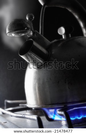 Steel kettle steaming by gas on a dark background