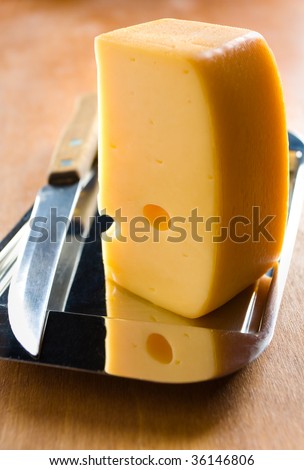Piece of swiss cheese on the metal plate with table knife