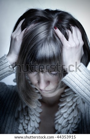 Portrait of the young woman with headache squeezing her head with hands, head down
