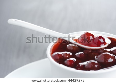 Closeup of gooseberry jam in the white ceramic bowl and ceramic spoon