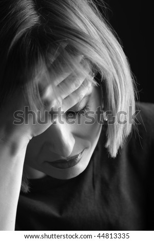 Portrait of sad woman, with her hand on the forehead, eyes closed, in black and white