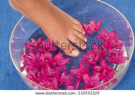 Feet in a bowl of water with pink blossoms
