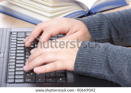 A young woman\'s hands typing on the keypad of a laptop