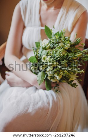 Bride in unusual wedding dress holding a wedding bouquet in a rustic style