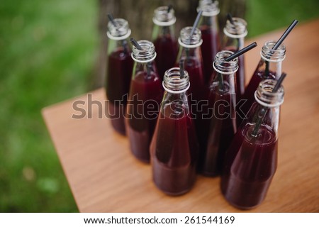 drink in bottles with a straw on a wooden table on a background of green grass