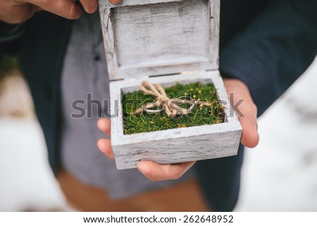 wedding rings in a wooden box on the moss in the hands of the friend of the groom
