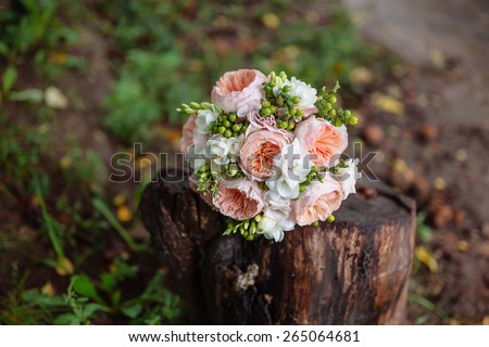 wedding bouquet of flowers and greenery lies in the forest on a wooden stump