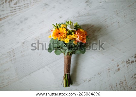 bouquet of orange flowers and green on a white wooden floor, wedding bouquet