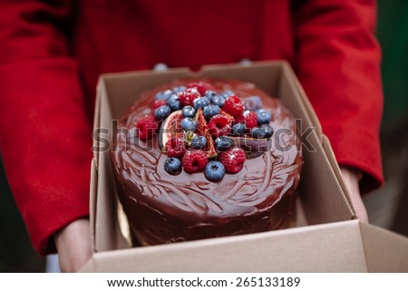 girl holding a box of chocolate cake with berries