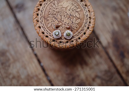 Earrings with gems on vintage wicker box on the wooden floor