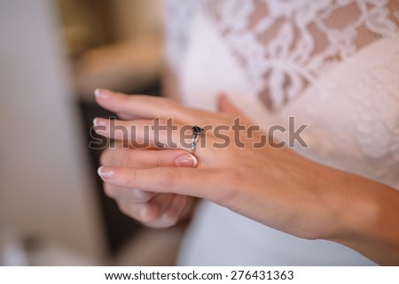 bride in a white lace dress corrects an engagement ring on the finger of white gold with a black jewel