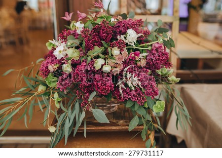 floral arrangement of lilacs and greens in a wooden hall