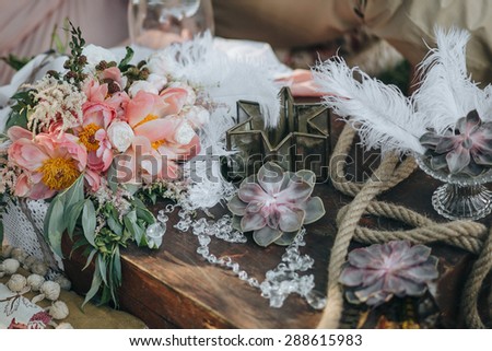 bouquet of pink and white peonies and greenery lies in an area decorated with succulents, feathers and vintage decor