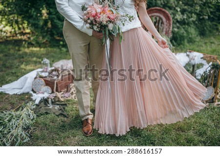 couple holding a bouquet of pink and white peonies and green on a background decorated area