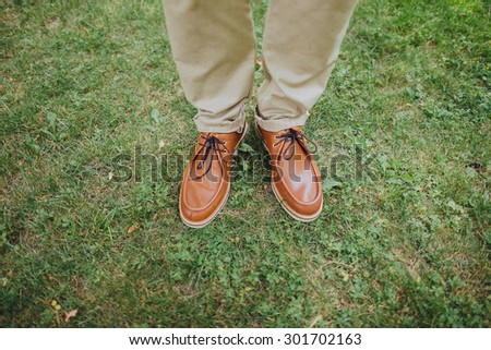 man in beige trousers and brown leather boots standing on the green grass