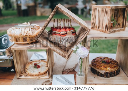 on decorated buffet table in wooden boxes are cakes and snacks