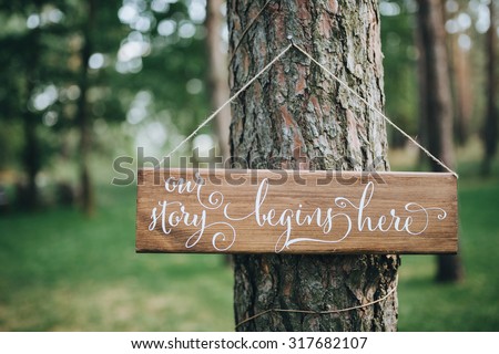 a wooden plaque with the inscription hanging on the tree in a pine forest