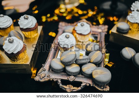cream cakes lie on a wooden stand on a table with a black cloth