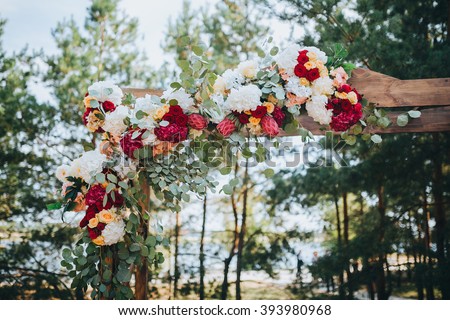 Wedding. Wedding ceremony. Arch. Arch, decorated with red and white flowers standing in the woods, in the wedding ceremony area