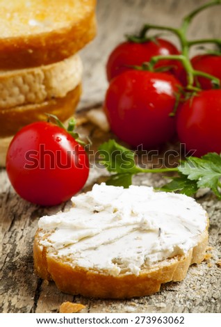 Home crostini with soft cheese and tomatoes on a wooden table, selective focus