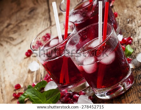 Fresh red juice cocktail with pomegranate seeds, mint and ice, selective focus