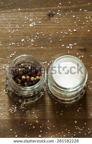 Spices: salt, pepper and herbs in small glass jar on a wooden table, top view, selective focus