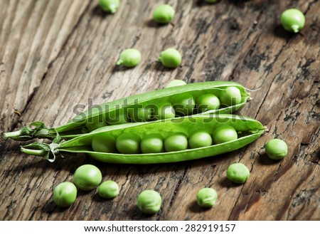 Opened green pea pods with peas in an old wooden table, selective focus