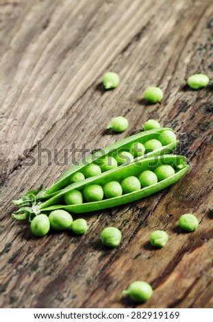 Opened green pea pods with peas in an old wooden table, selective focus