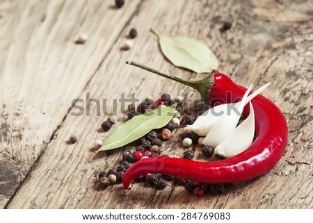 Red hot chili peppers and spices, garlic and bay leaf on old wooden table, selective focus