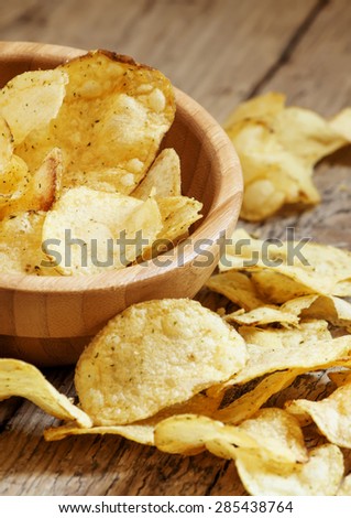 Golden potato chips in a wooden bowl on the old table, selective focus