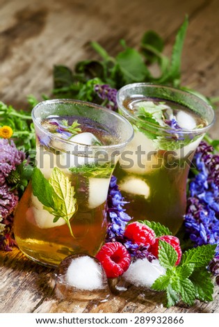 Herbal flower iced tea with raspberries and ice in Islamic glasses, selective focus