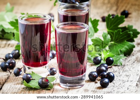 Fresh black currant juice with berries in glasses on an old wooden table, selective focus
