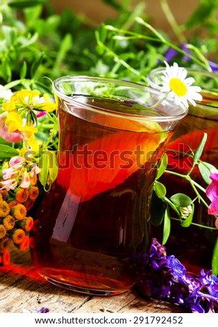 Black tea with lemon and herbs in an authentic Middle Eastern glasses on an old wooden table, selective focus