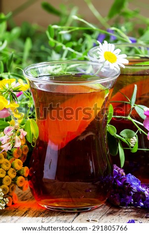 Black tea with lemon and herbs in an authentic Middle Eastern glasses on an old wooden table, selective focus