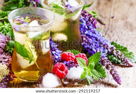 Herbal flower iced tea with raspberries and ice in Islamic glasses, selective focus