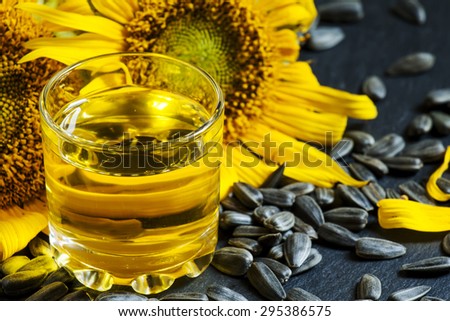 Fresh sunflower oil in a glass with flowers sunflowers and sunflower seeds, selective focus