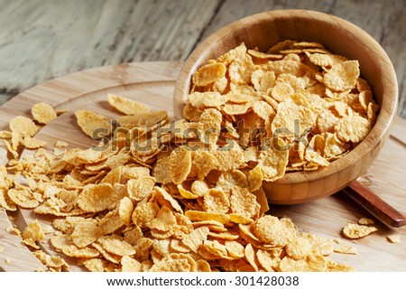 Corn flakes poured out of a wooden bowl, selective focus