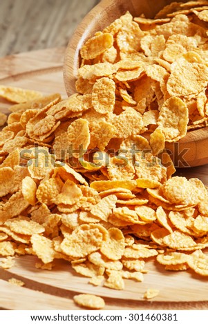 Corn flakes poured out of a wooden bowl, selective focus